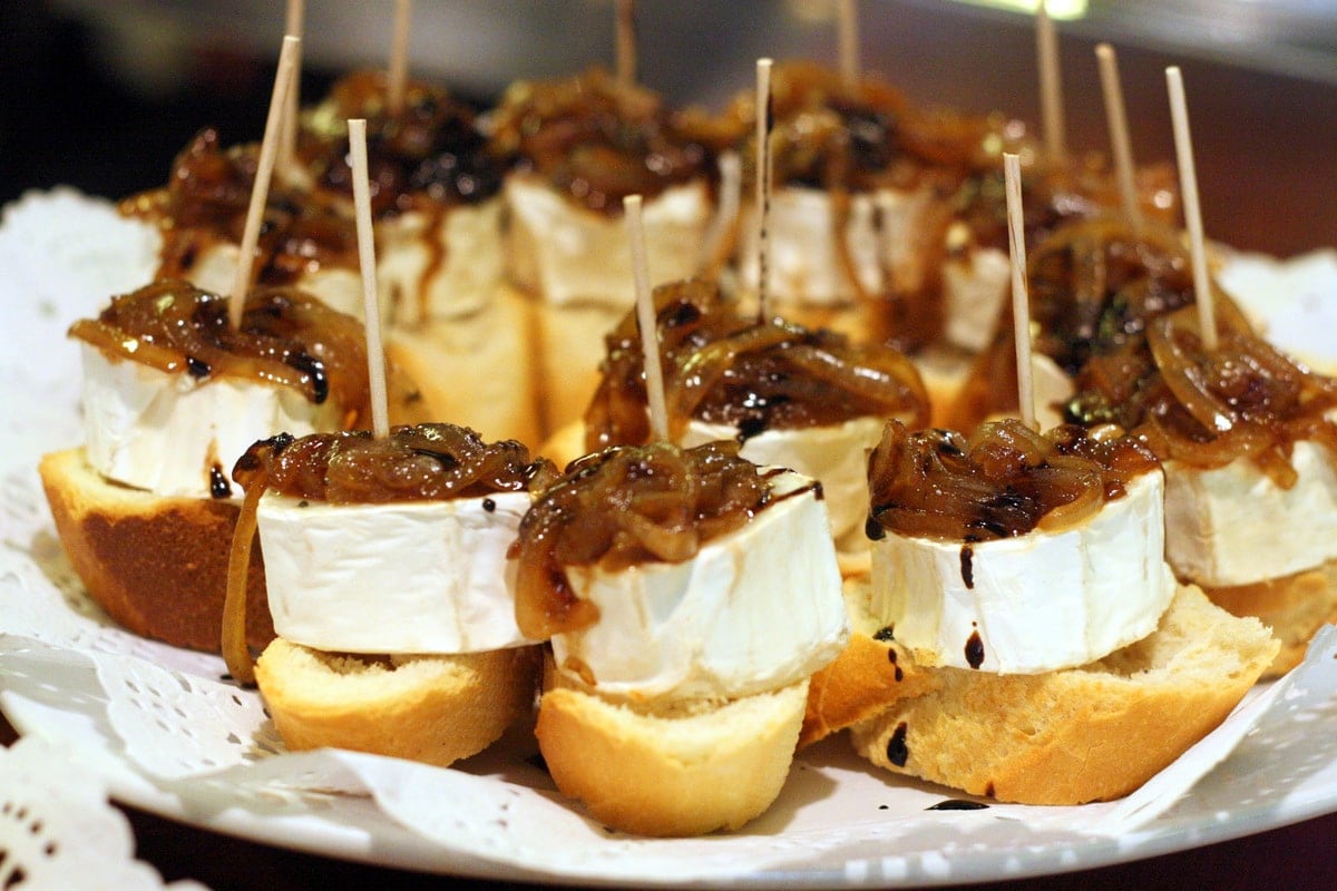 Small pieces of crusty bread topped with goat cheese and caramelized onions, all held together with a toothpick.