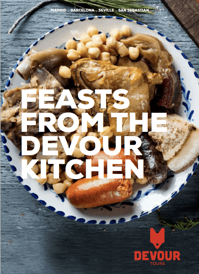 Cookbook cover reading Spanish Feasts from the Devour Tours Kitchen on top of a Spanish stew photo