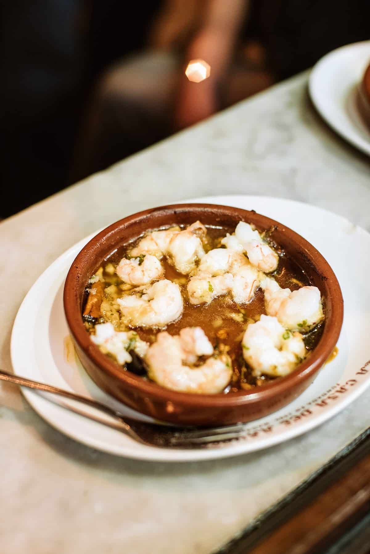 Garlic shrimp served in a small clay dish.