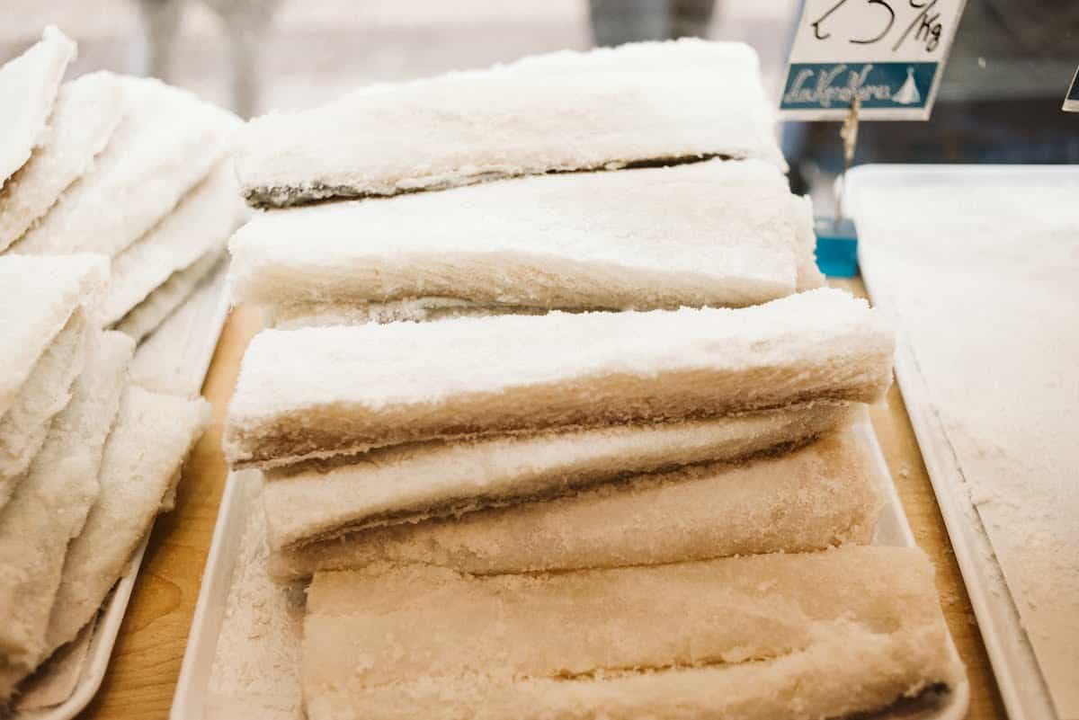 Piles of uncooked cod fillets preserved in salt. 