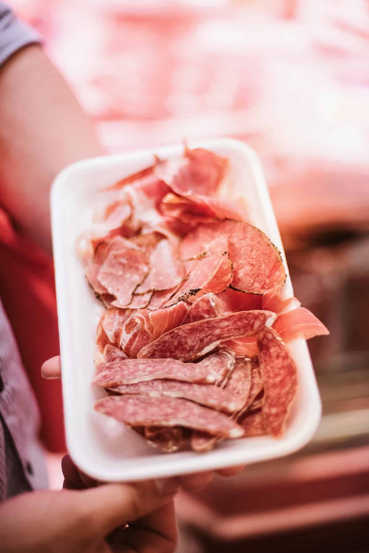 Three types of Spanish cured meats on a small white tray.