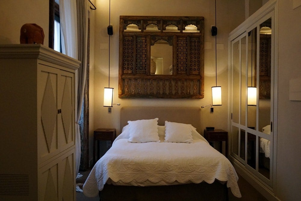 A cozy room at Hotel Corral del Rey, with a white bed and wooden wall art