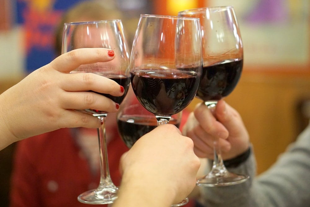Close-up of four glasses of red wine raised in a toast.