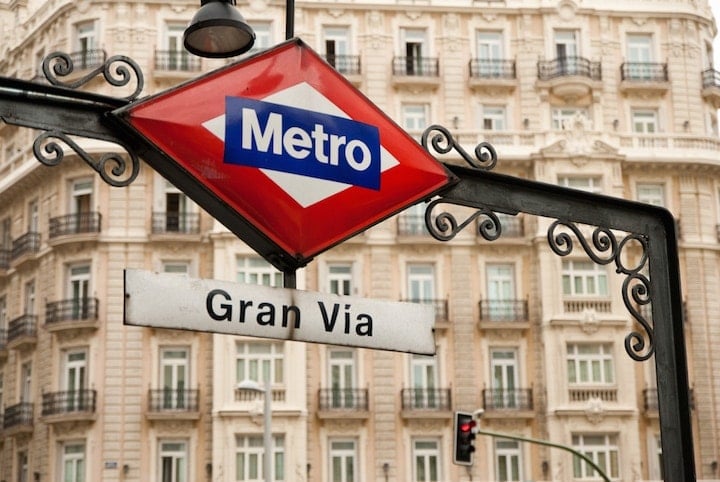 Close-up of the Gran Via metro sign, with a large ornate building behind it.