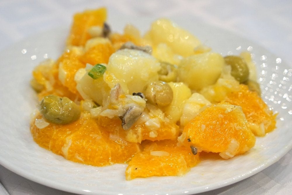 Close-up of a plate of Malaga salad with oranges, olives, and salt cod.