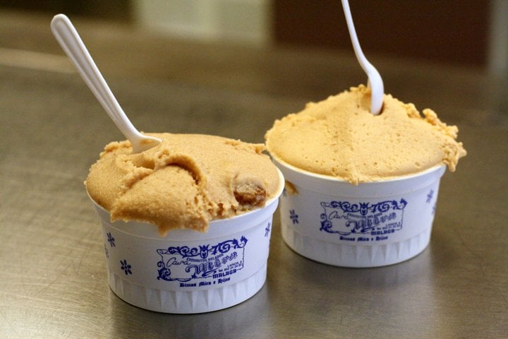 Two small cups of ice cream with spoons sticking out. 