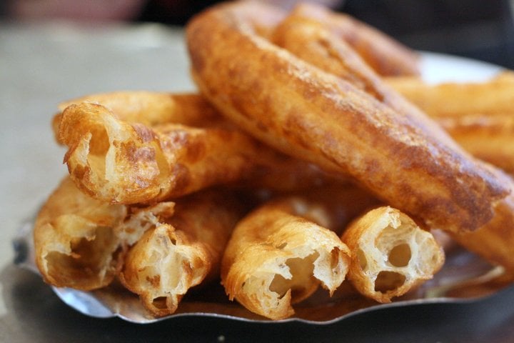 Close-up of a plate of golden brown churros with light and airy centers.
