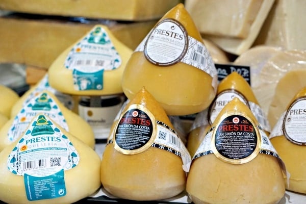 A table of cone-shaped Tetilla cheeses, ranging from light yellow to golden brown.