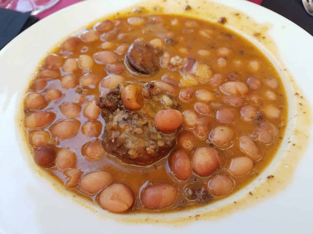 Bean stew with sausage in a white bowl