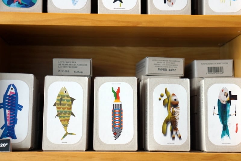 Wooden shelf with several boxes of tinned seafood, each with an artistic representation of a fish.