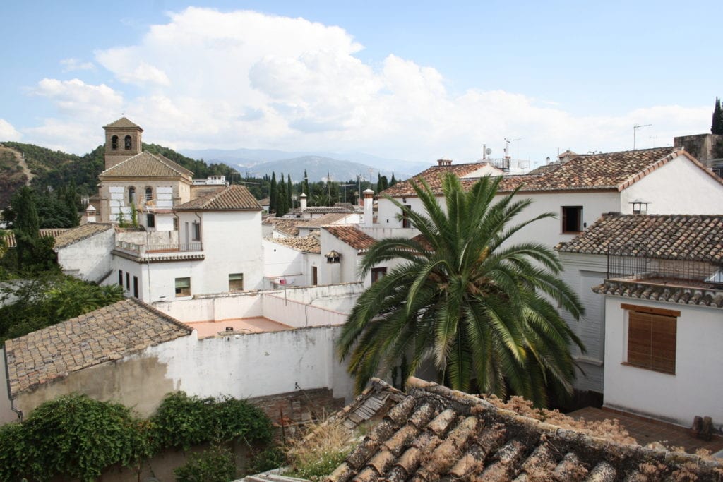 Whitewashed buildings, tiled roofs, and a palm tree in the Albaicín