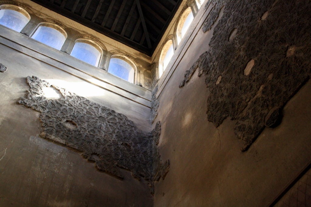 The inside of a building in the Alhambra, with high windows and ancient tile fragments