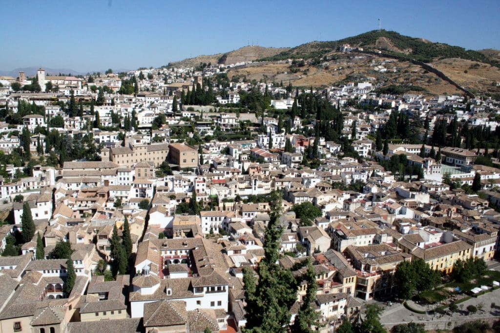 A view of Granada's Albaicín neighborhood from above, full of whitewashed houses and trees