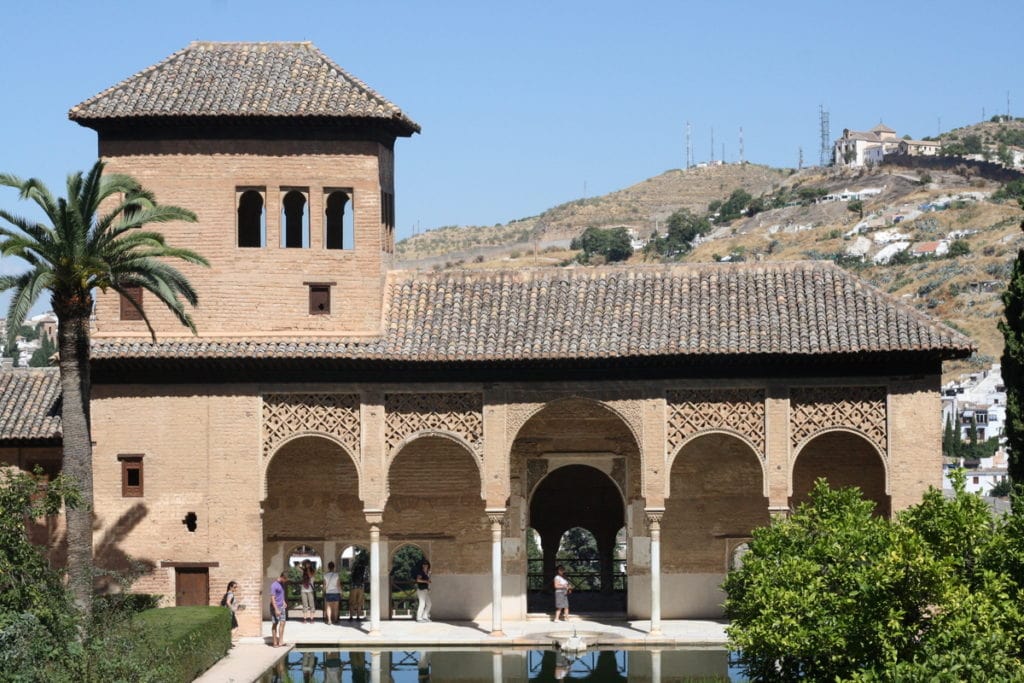 One of the buildings of the Alhambra, with intricate archways and a small pool in front