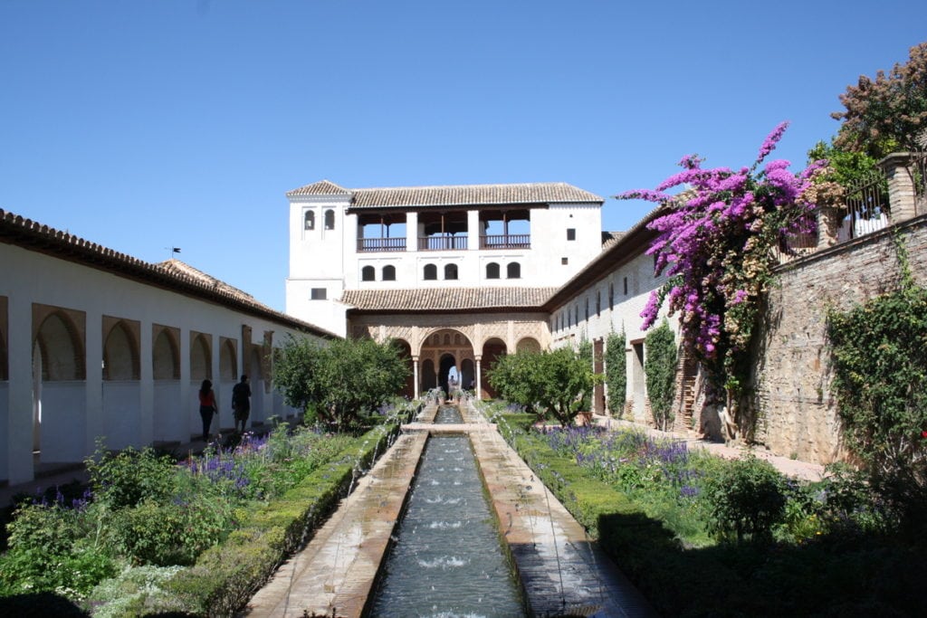 A long fountain in a courtyard of the Alhambra with a building in the background