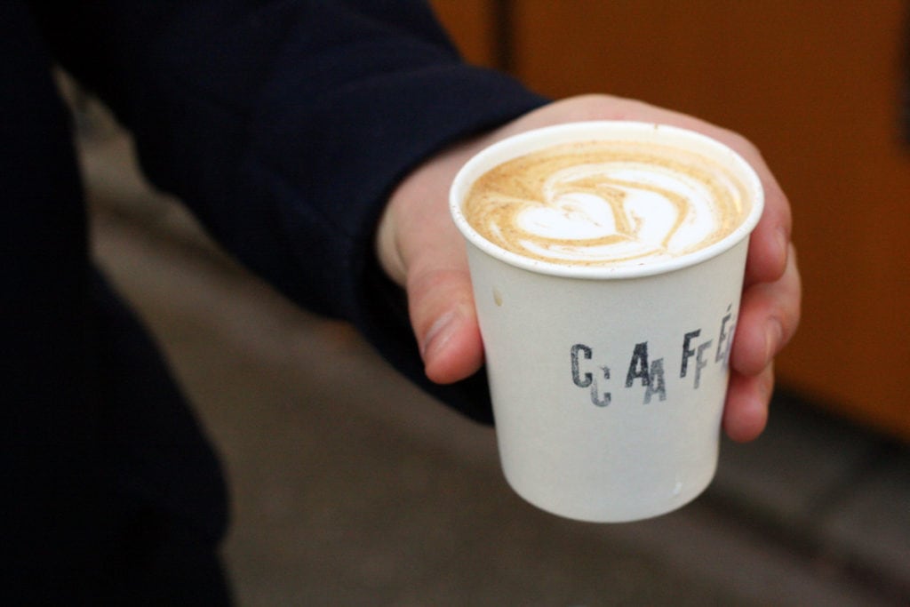 Close-up of someone holding a to-go coffee cup with heart-shaped latte art