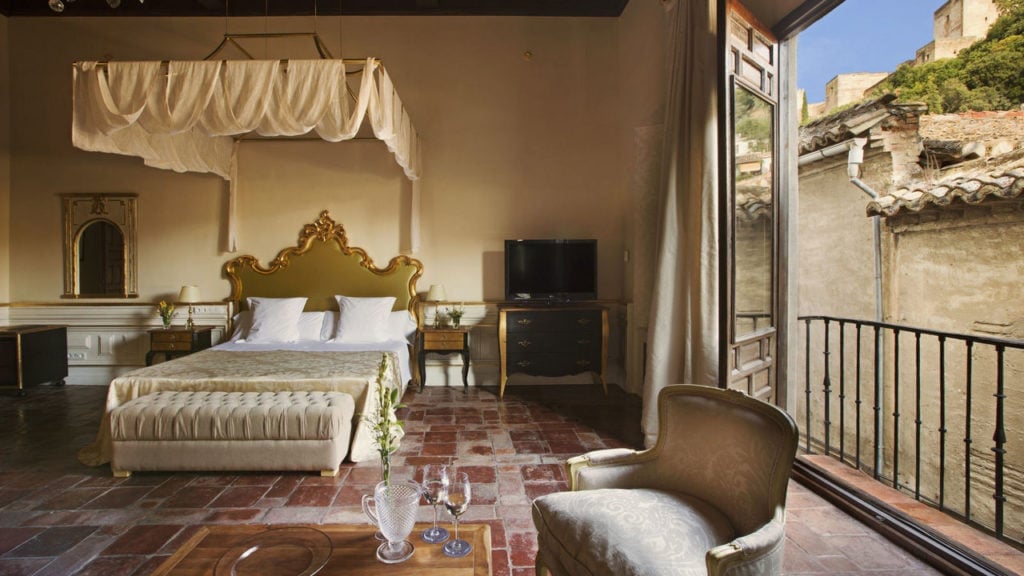 An elegant hotel room with a balcony and views of Granada's historic buildings