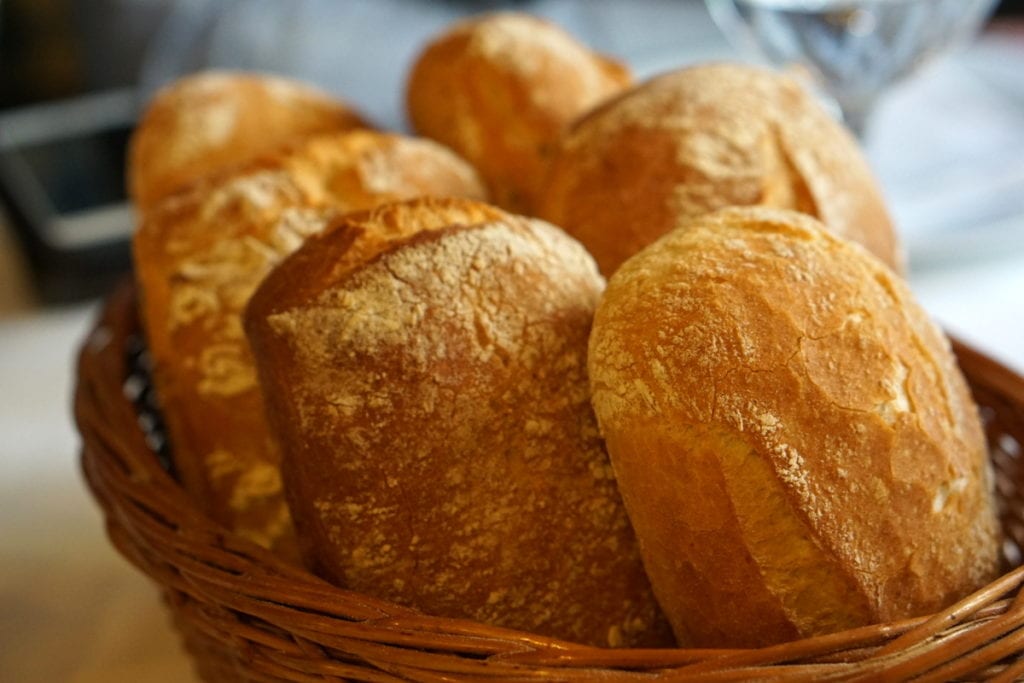 Close-up of six oblong, crusty loaves of bread in a wicker basket.