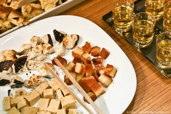 Different Turrón cut up on a white plate and served next to shot glasses of liquor.
