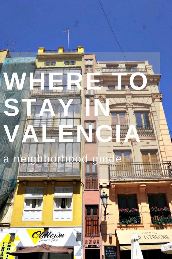 Two colorful buildings in Valencia with ornate iron balconies and a narrow building between them