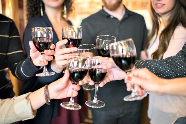 A group of people clinking their glasses of red wine together in a toast