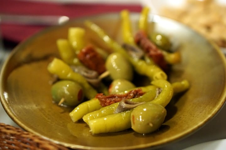 A small dish of gildas: skewered green olives, pickled peppers, and anchovies.