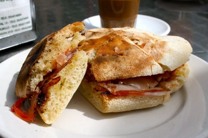 A cured ham sandwich on toasted round bread, cut in half.