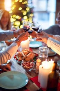 A family toasting with glasses of red wine over a table set for a Thanksgiving meal