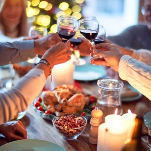 A family toasting with glasses of red wine over a table set for a Thanksgiving meal