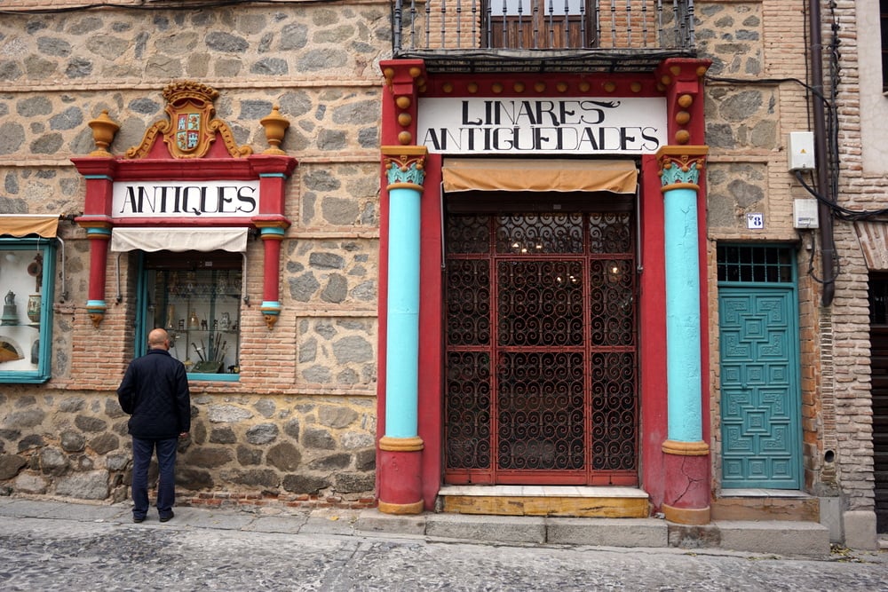 An antiques shop with a red and blue entrance with old-fashioned writing and ornate details.
