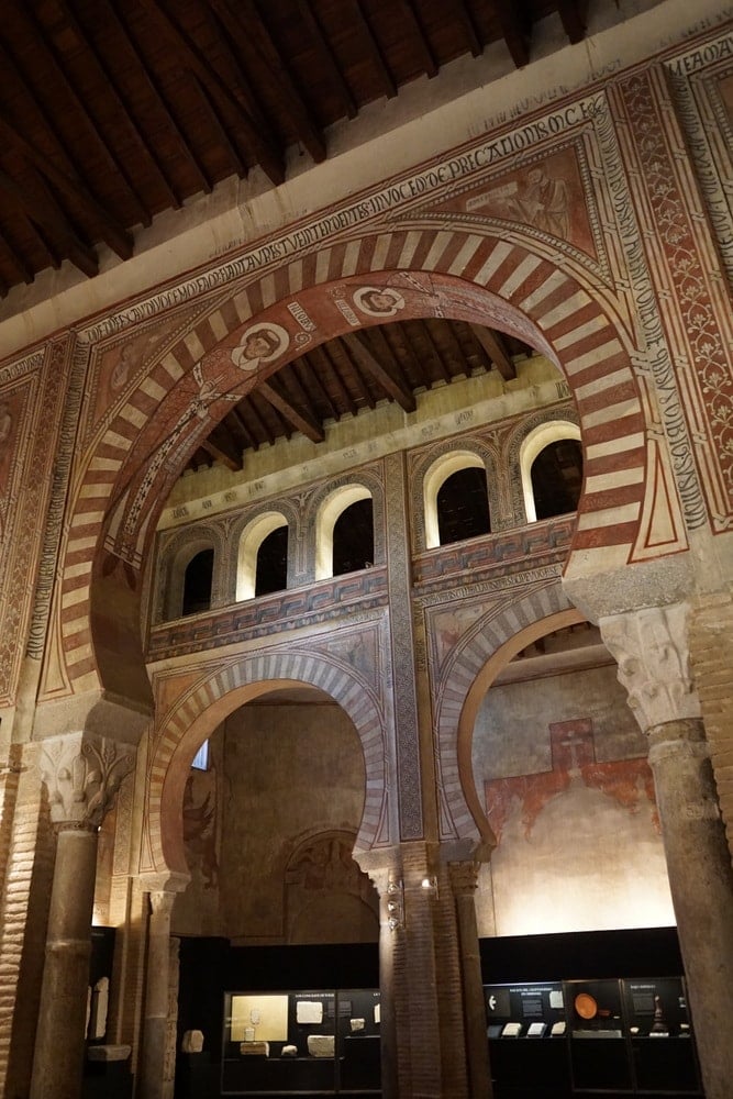 Striped, horseshoe-shaped arches in the church of San Román, with museum exhibits below them.