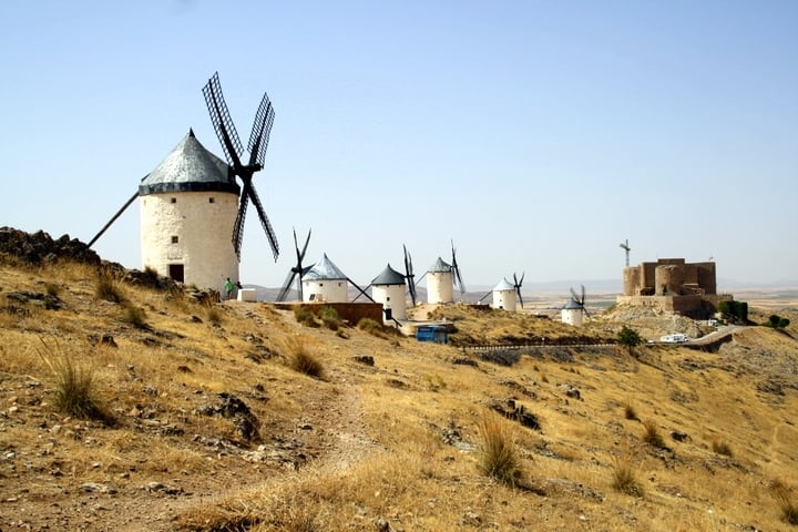 Six traditional whitewashed windmills on top of a dry and dusty hill in Consuegra.