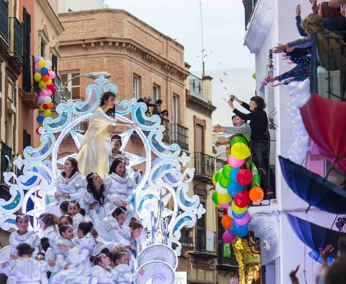 A float passes in front of a balcony with spectators during a Three Kings Day parade.