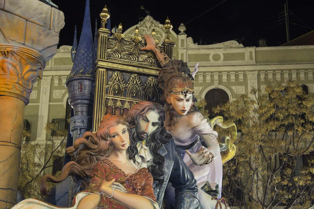 A gigantic paper sculpture of 3 human figures and an ornate castle.
