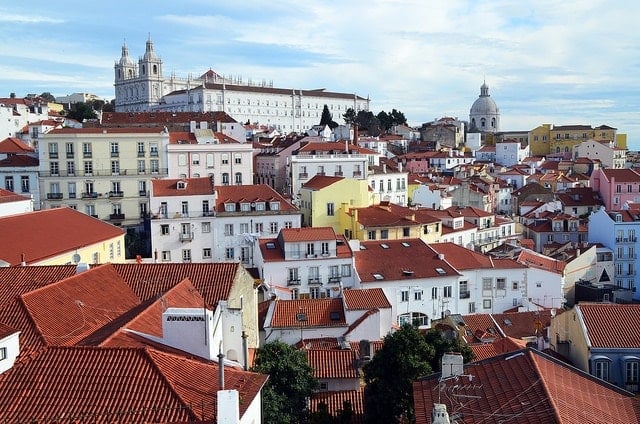 A panoramic view of Lisbon's colorful buildings and tiled rooftops on a large hillside.