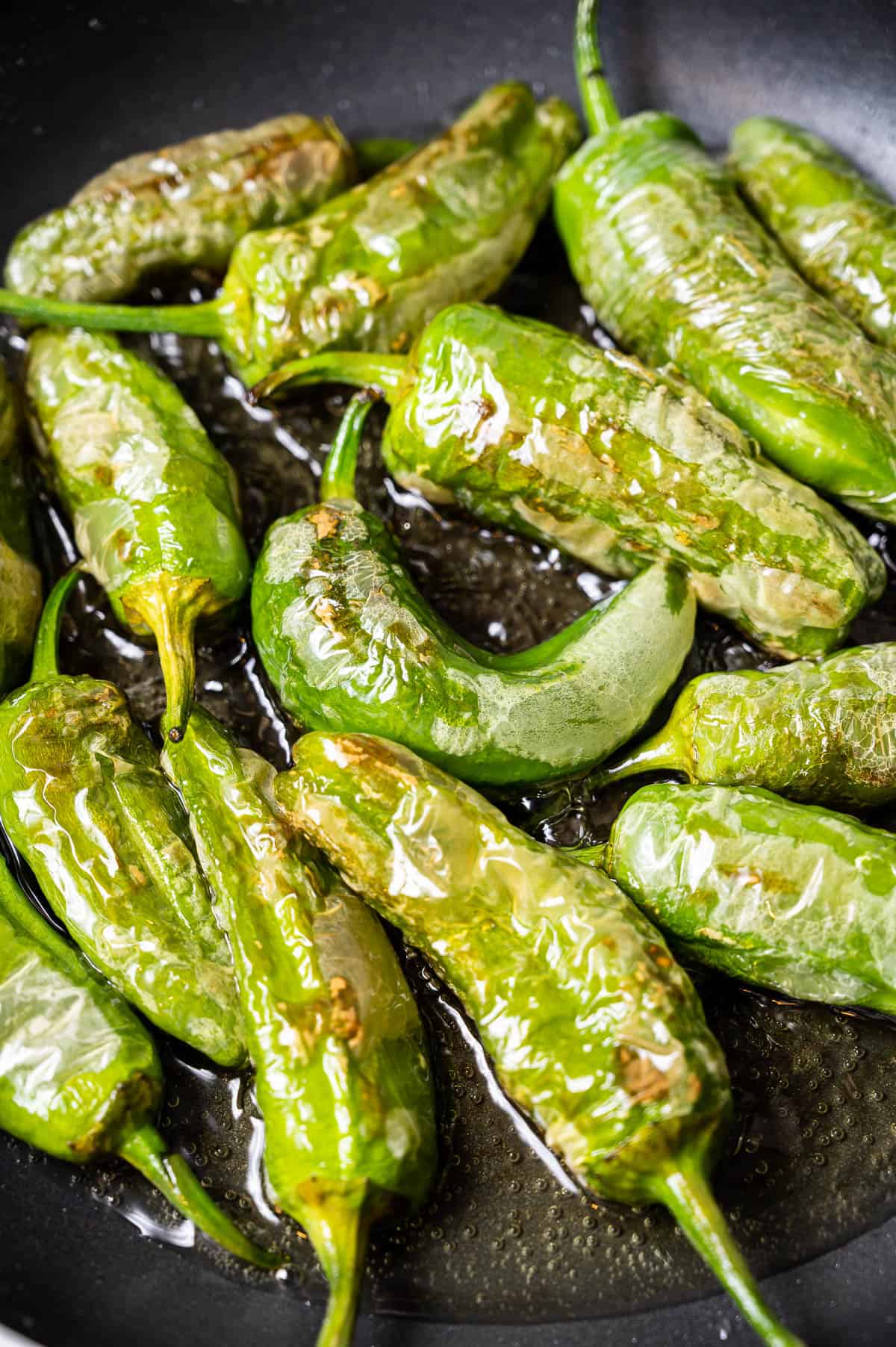 Padron peppers frying in a cast iron skillet
