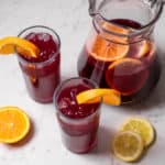 pitcher of tinto de verano with citrus fruit and two tall glasses