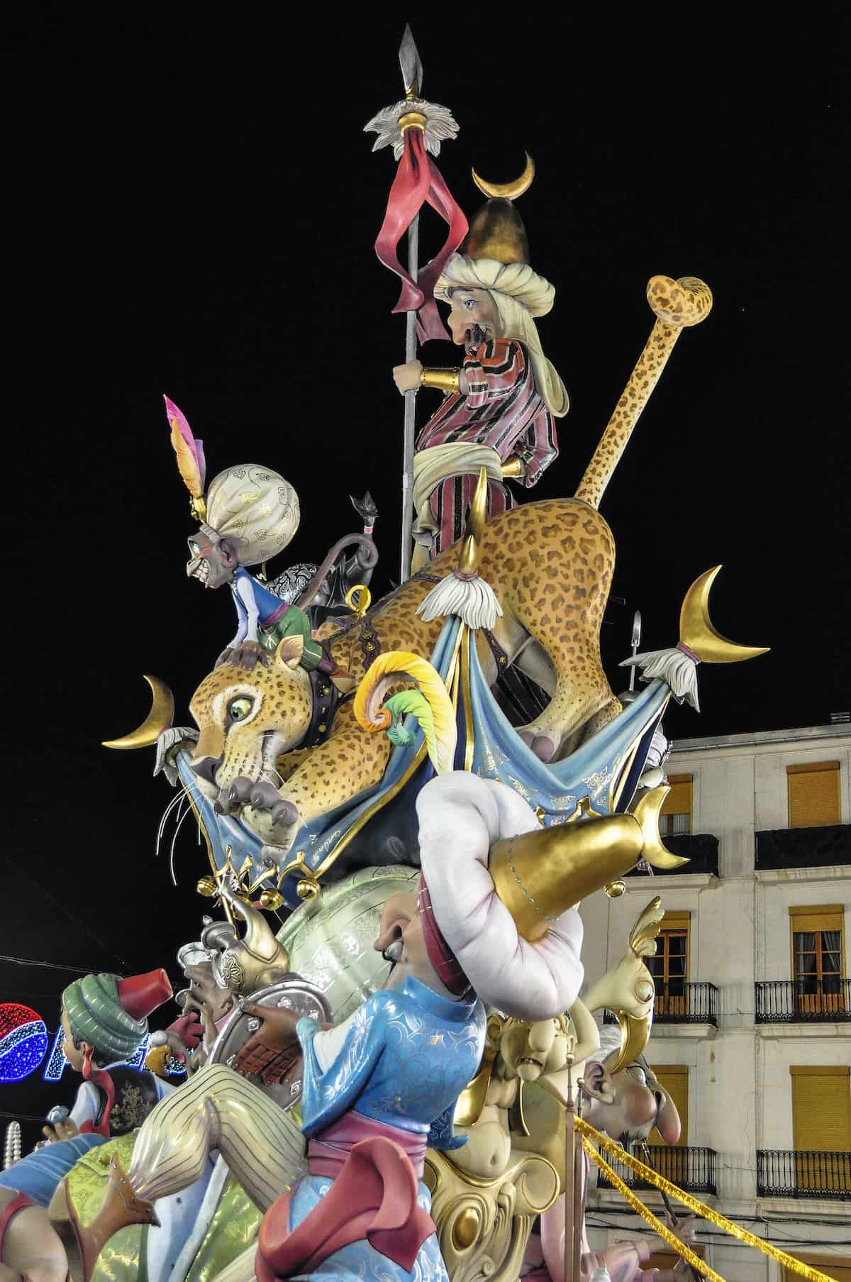 A giant paper sculpture of a leopard and colorful fantasy characters against the night sky.