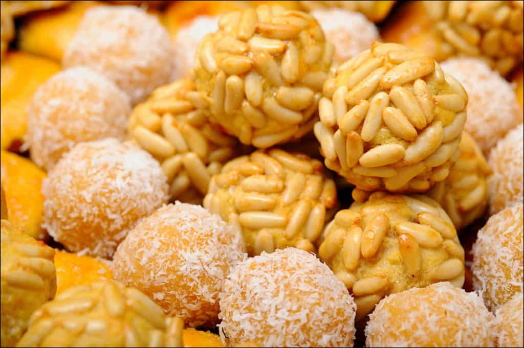 Close-up of a tray of round marzipan sweets covered in pine nuts.