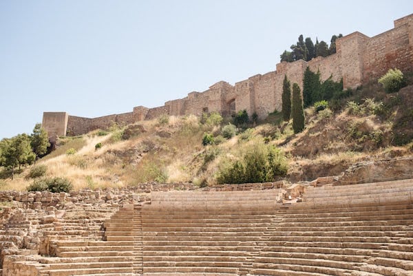 Hillside with a stone wall at the top and an ancient stone amphitheater below it.