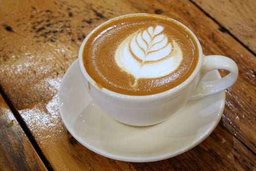 A cup of coffee with latte art sitting on a wooden table