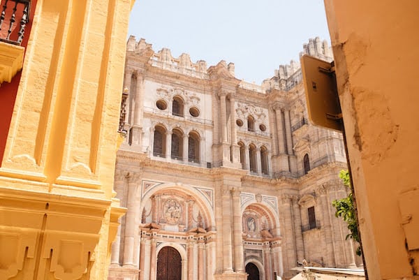 A view of the ornate stone facade of Malaga's cathedral, from across the plaza.