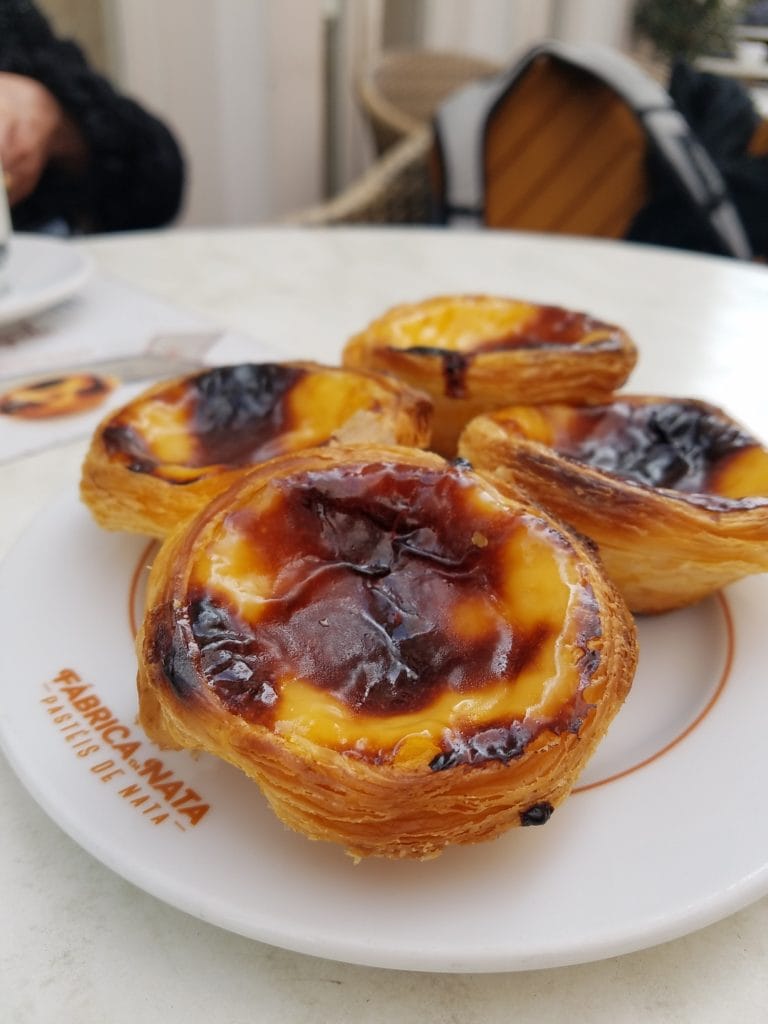 Close-up of four custard tarts on a plate, with crispy pastry shells and blackened tops.