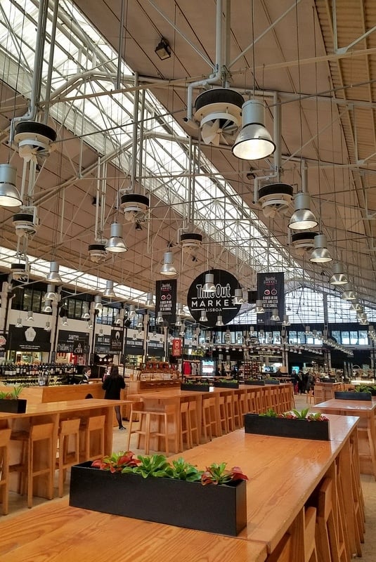Long empty wooden tables at Lisbon's Time Out Market, a large food hall.