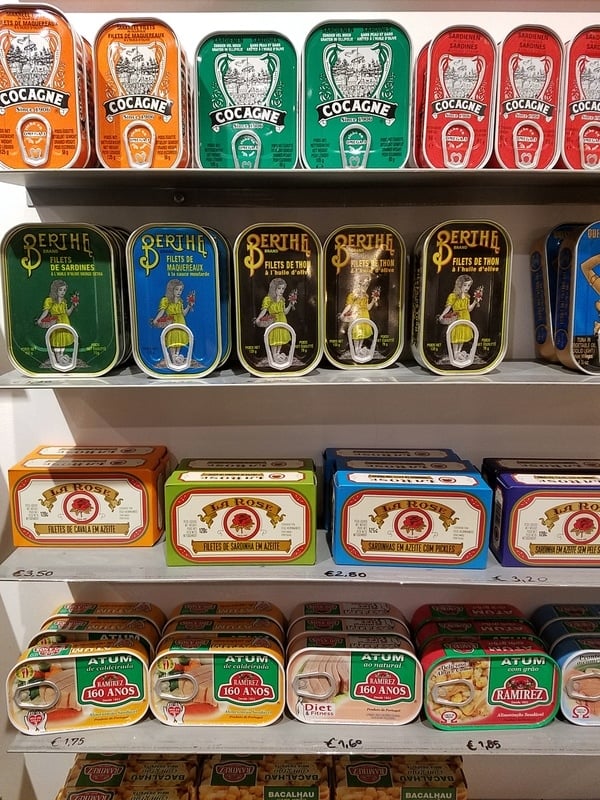 Shelves of canned seafood in colorful packaging.