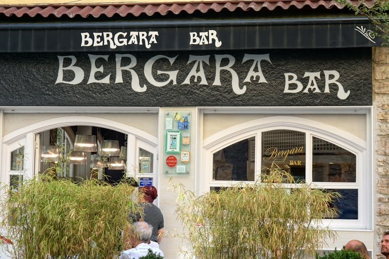 The facade of Bar Bergara in San Sebastián, with a black awning and arched windows