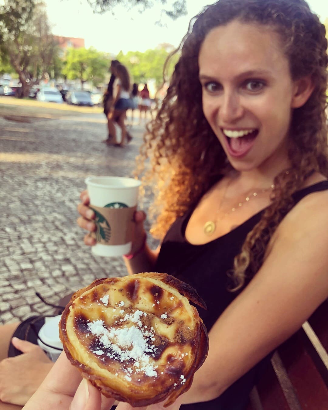 Close-up of a custard tart with a woman smiling at it with excitement in the background. 