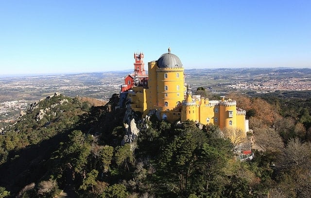 Panoramic view of the yellow and red Pena Palace perched high in the mountains of Sintra.