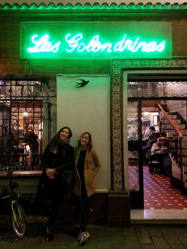 Two women smile in front of Las Golondrinas, a traditional tapas bar in Seville