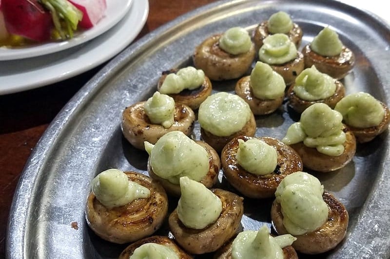 A metal plate of mushrooms topped with garlic alioli